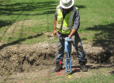 SUE crew member working on land development with tool in ground